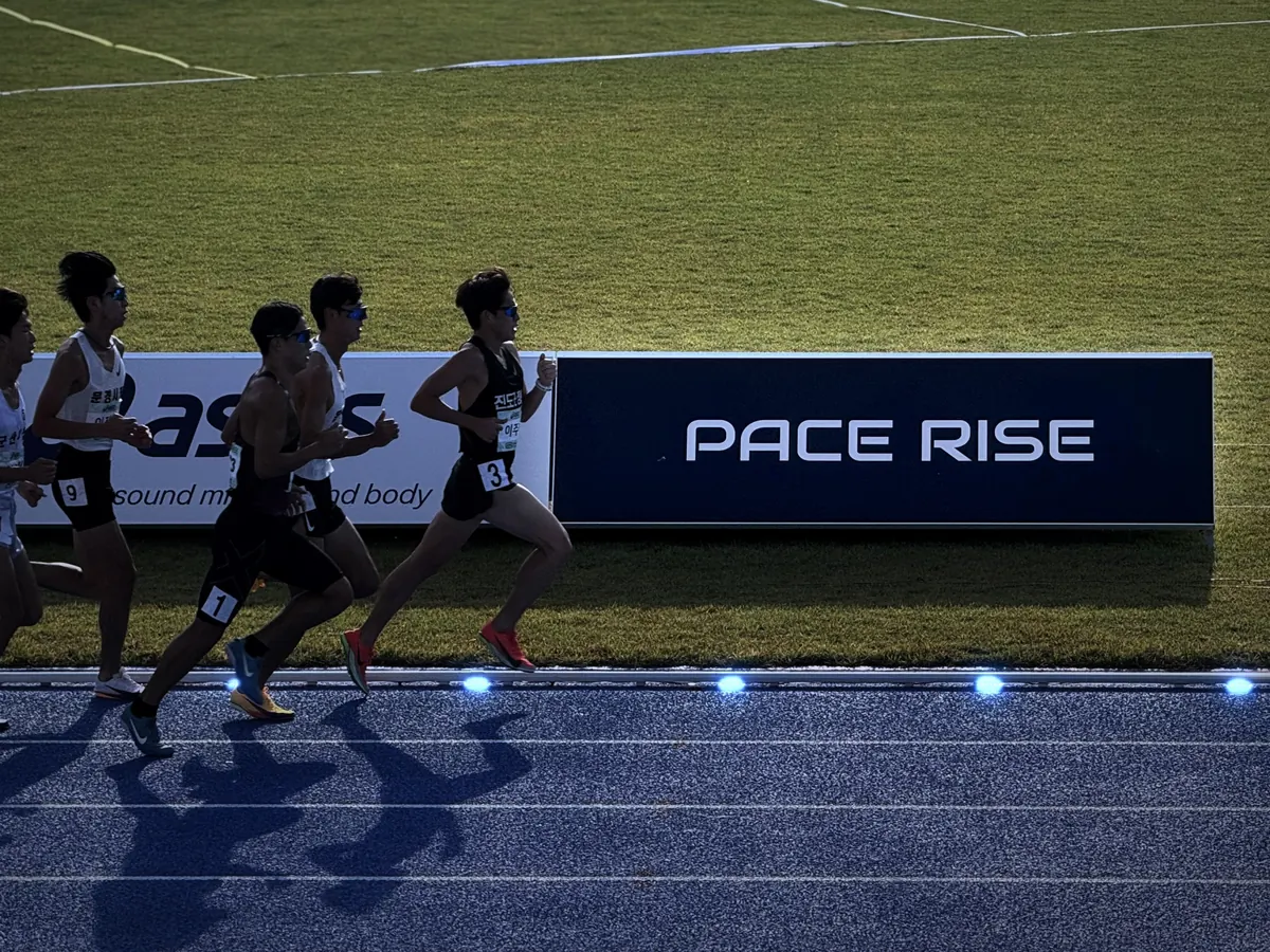 블루 트랙 위 LED 페이싱 라이트를 따라 달리는 선수들과 PACE RISE 보드